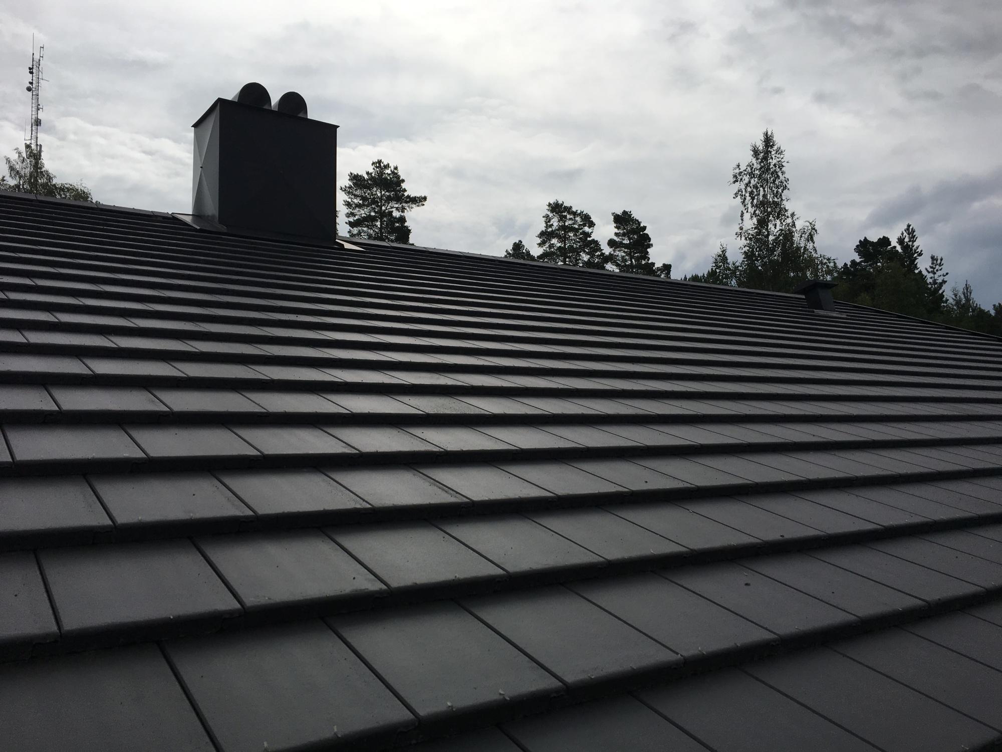 Nytt tak med svart flat takstein og pipe